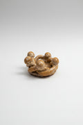 Small ceramic sculpture of a group of people huddled together on a plain background