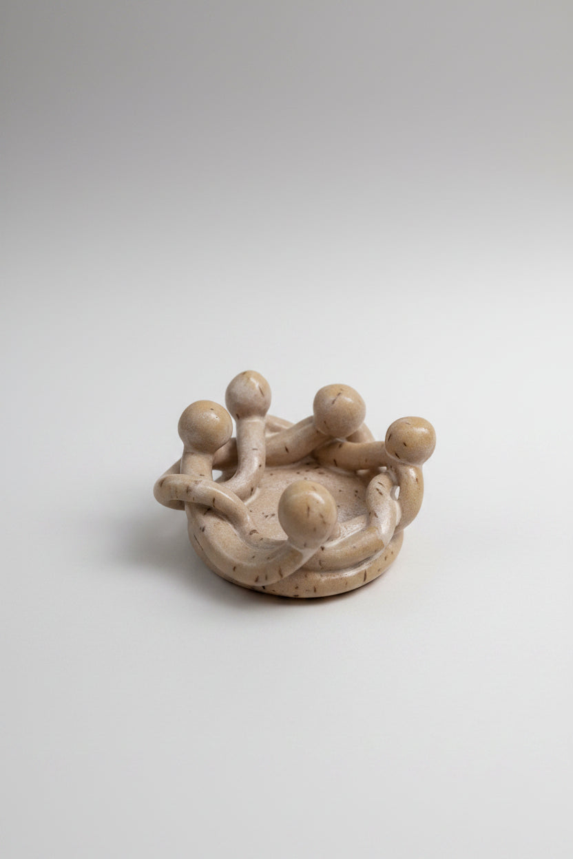 Small ceramic sculpture of a group of people on a white surface with a gray background