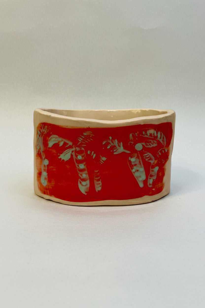 Ceramic planter with red design on a beige background